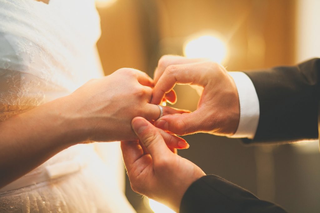 A groom putting the ring on the bride