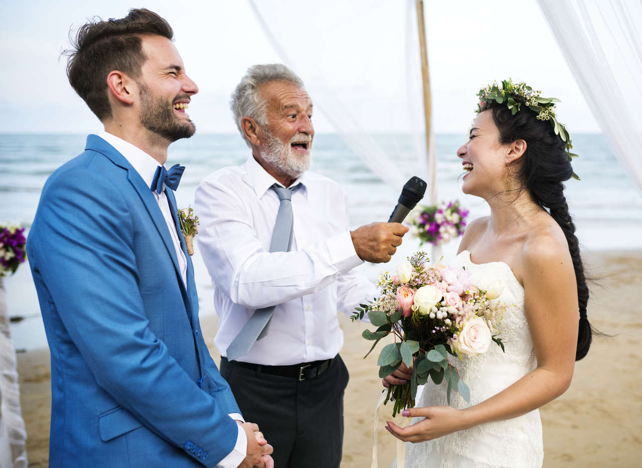 A young couple getting married laughing with their officiator