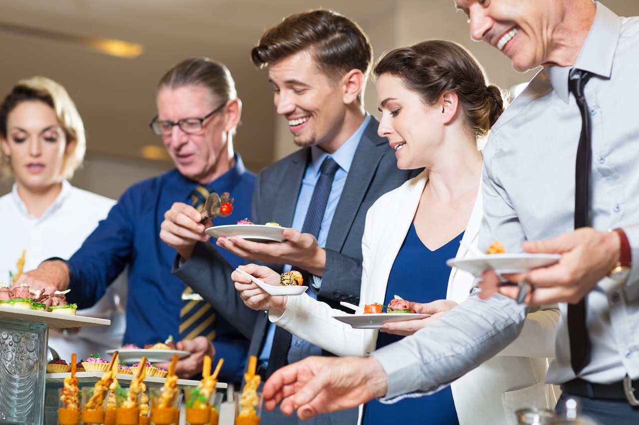 People lining up getting food at a buffet happily