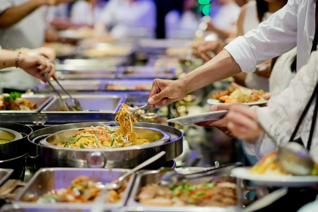 Close up of hands getting food from a buffet