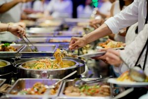 Close up of hands getting food from a buffet