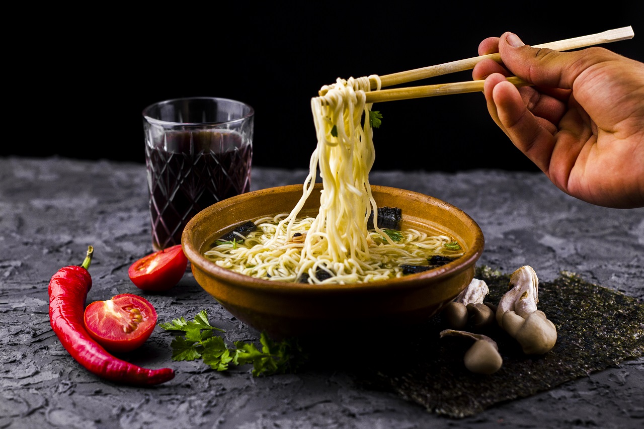 Chopsticks holding up long pieces of noodles