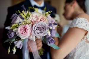 A bride and groom holding up the flower bouquet