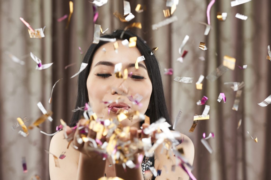 A debutante blowing confetti