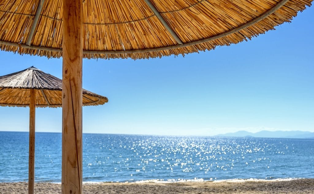 Reed umbrellas and sun beds at the empty beach in Asprovalta